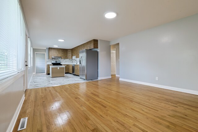 kitchen featuring backsplash, light hardwood / wood-style flooring, a kitchen island, and appliances with stainless steel finishes