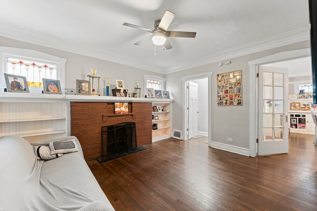 living room featuring dark hardwood / wood-style flooring, a brick fireplace, ceiling fan, and crown molding