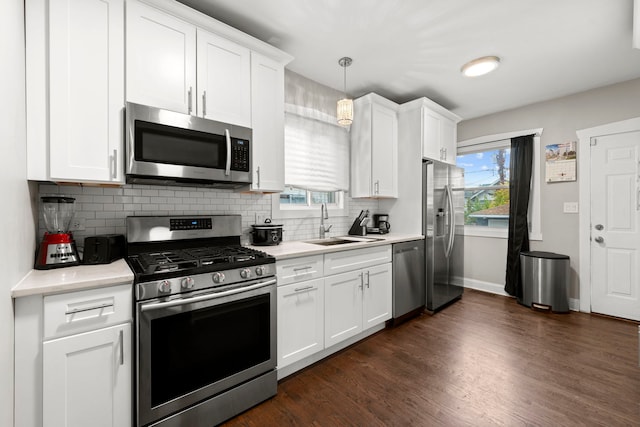 kitchen featuring backsplash, stainless steel appliances, decorative light fixtures, white cabinets, and dark hardwood / wood-style floors