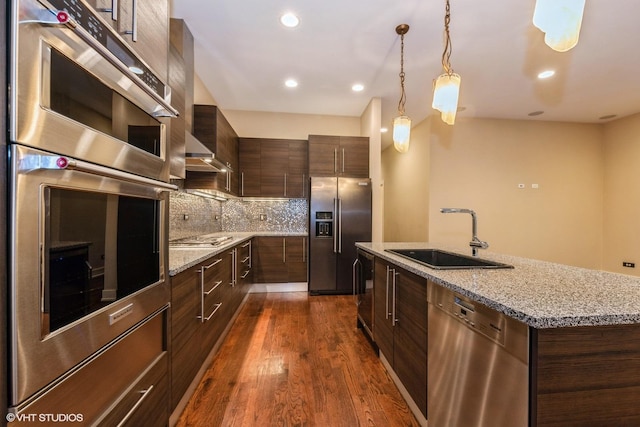 kitchen featuring backsplash, a kitchen island with sink, dark wood-type flooring, sink, and stainless steel appliances