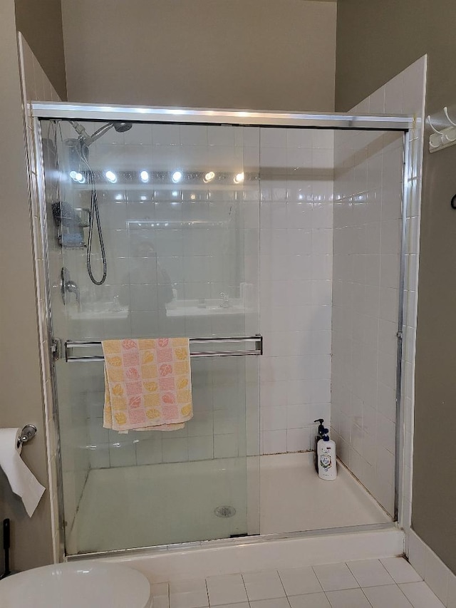 bathroom with tile patterned flooring, toilet, and a shower with door