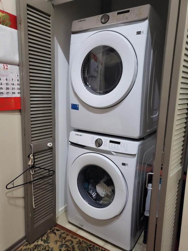 laundry room featuring light tile patterned floors and stacked washer and clothes dryer