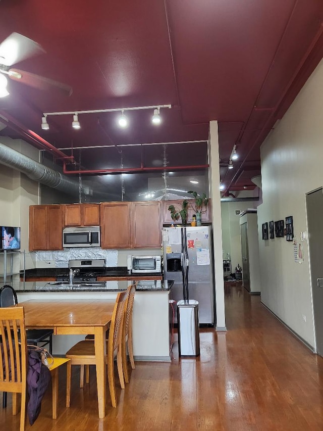 kitchen featuring track lighting, sink, tasteful backsplash, wood-type flooring, and stainless steel appliances