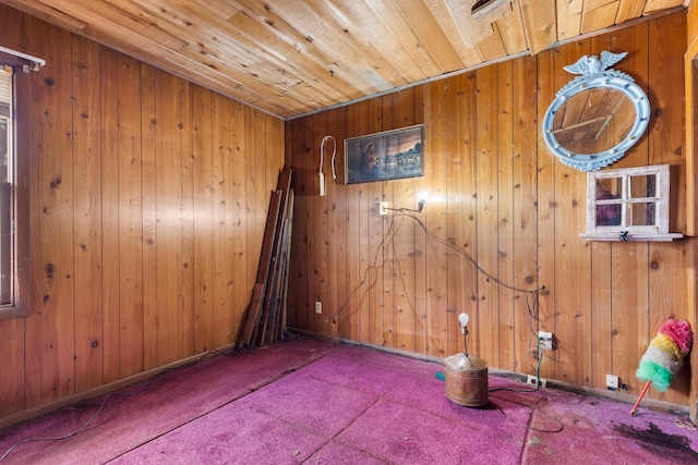 carpeted spare room with wooden ceiling and wood walls