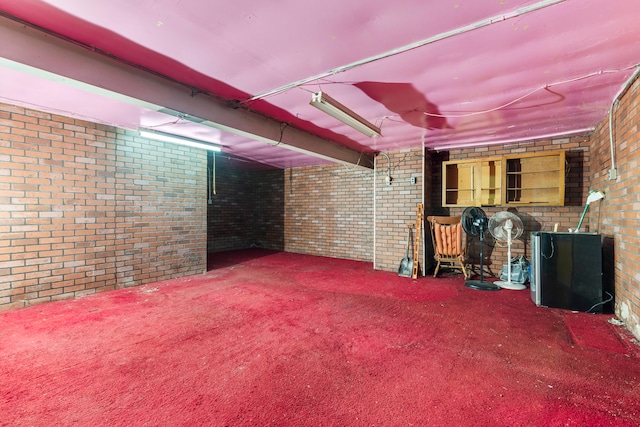 basement featuring carpet flooring and brick wall