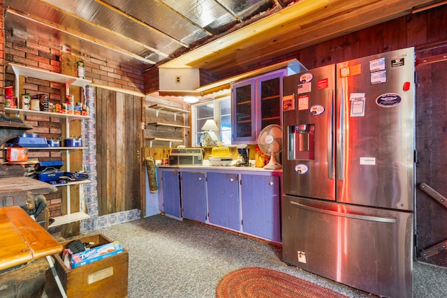 kitchen featuring wood walls, dark carpet, and stainless steel refrigerator