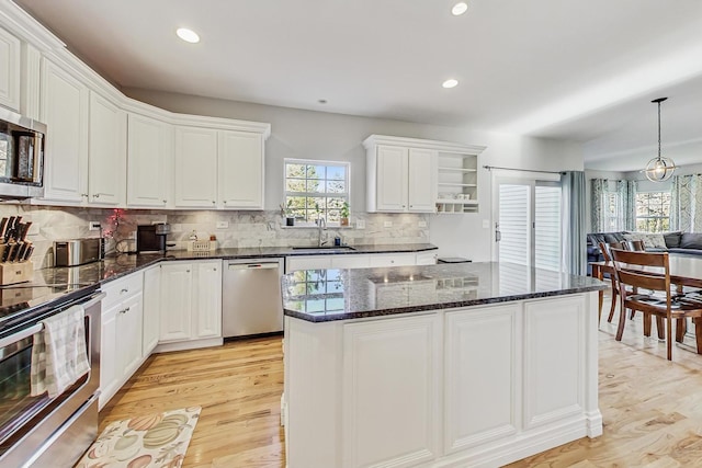 kitchen with pendant lighting, light hardwood / wood-style floors, white cabinetry, and stainless steel appliances