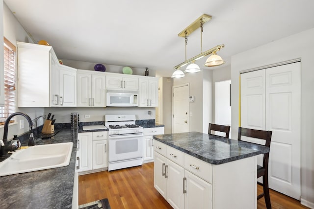 kitchen featuring sink, a kitchen breakfast bar, decorative light fixtures, white appliances, and white cabinets