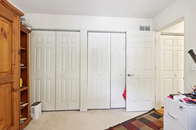 interior space featuring light colored carpet and two closets