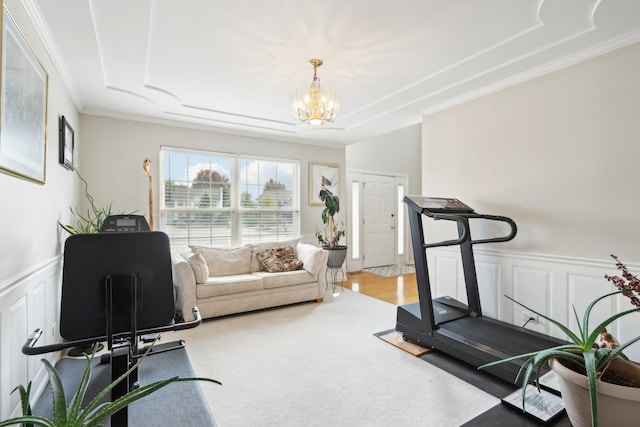 exercise room with crown molding, light hardwood / wood-style flooring, and an inviting chandelier