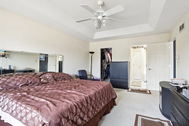 carpeted bedroom featuring ceiling fan, a raised ceiling, a spacious closet, and a closet