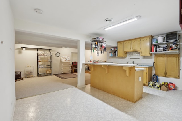 kitchen featuring a breakfast bar, light brown cabinetry, kitchen peninsula, and light colored carpet