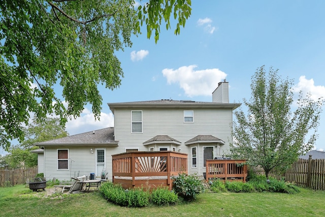 back of house featuring a lawn, a fire pit, and a deck