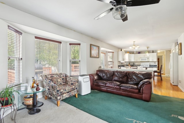 living room with light hardwood / wood-style floors and ceiling fan with notable chandelier