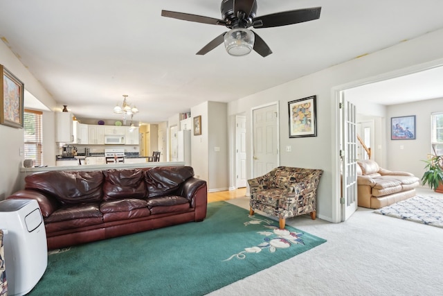 carpeted living room with plenty of natural light and ceiling fan with notable chandelier