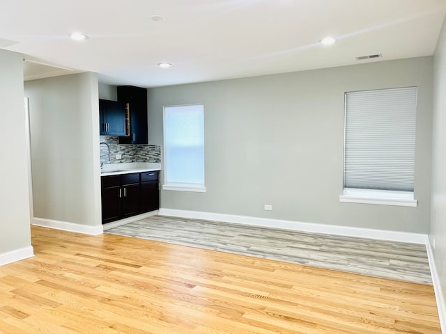 interior space with backsplash, light hardwood / wood-style flooring, and sink