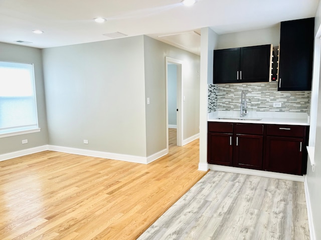 kitchen featuring backsplash, light wood-type flooring, and sink