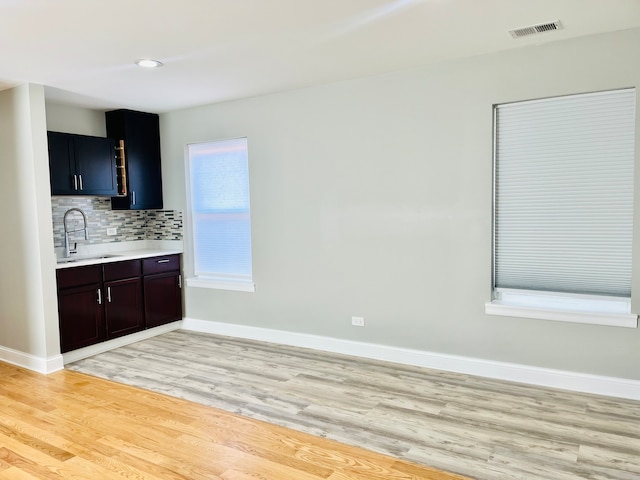 kitchen featuring tasteful backsplash, dark brown cabinetry, sink, and light hardwood / wood-style floors