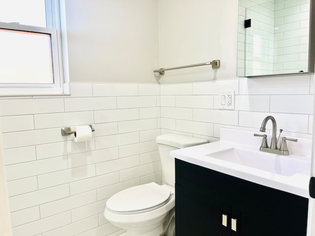 bathroom with vanity, toilet, and tile walls