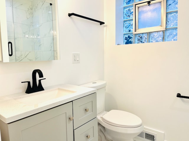 bathroom featuring vanity, a shower with shower door, and toilet