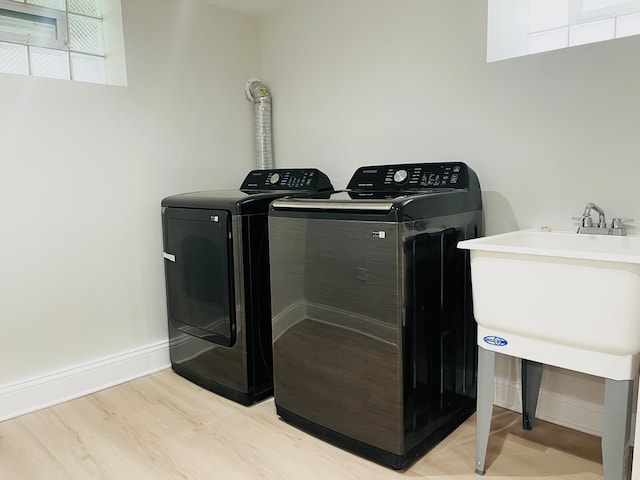 clothes washing area featuring light wood-type flooring and washing machine and clothes dryer