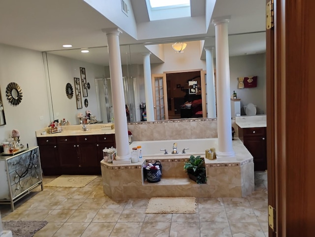 bathroom featuring tile patterned flooring, vanity, and tiled bath