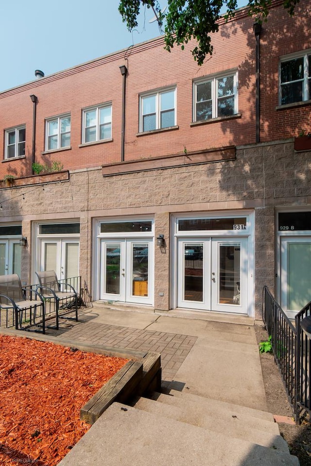 rear view of property with a patio area, french doors, and brick siding