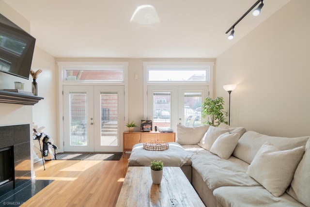 living area featuring french doors, track lighting, wood finished floors, and a tiled fireplace