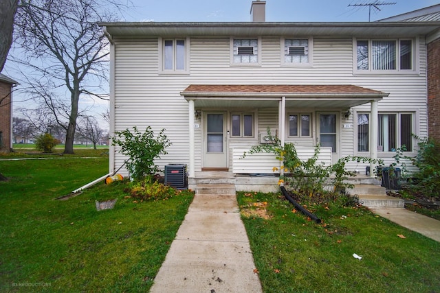 townhome / multi-family property with cooling unit and a front lawn