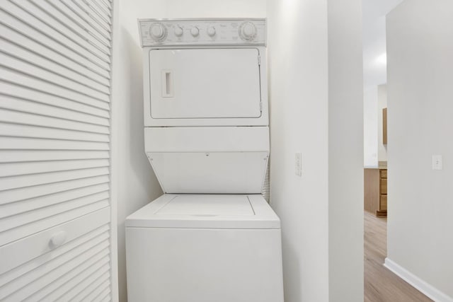 washroom with stacked washer / dryer and light hardwood / wood-style flooring