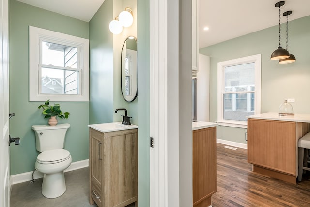 bathroom with toilet, vanity, and wood-type flooring