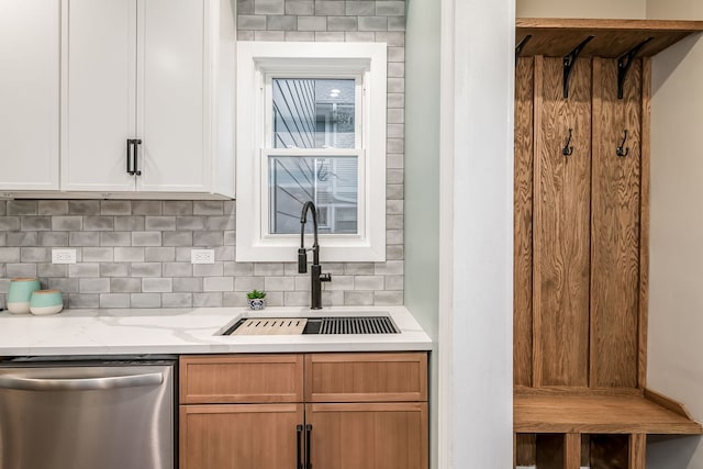 kitchen featuring sink, white cabinetry, stainless steel dishwasher, light stone countertops, and decorative backsplash