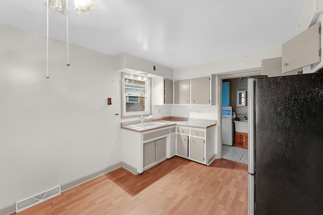 kitchen featuring decorative backsplash, light wood-type flooring, stainless steel refrigerator, and sink