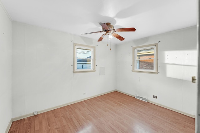 spare room featuring ceiling fan, crown molding, and light wood-type flooring