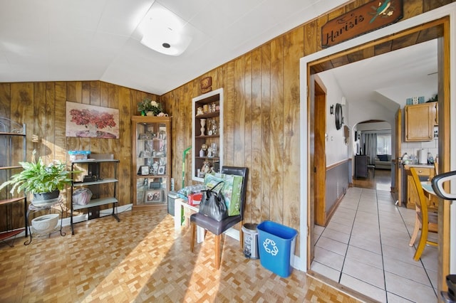 interior space with built in shelves, wood walls, light tile patterned flooring, and vaulted ceiling