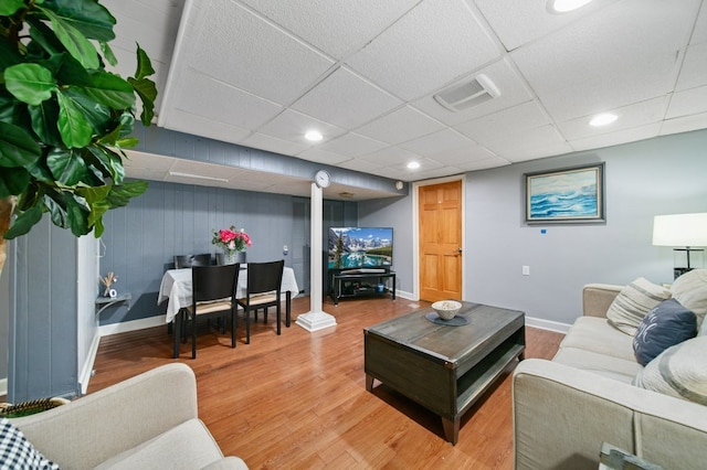 living room featuring hardwood / wood-style floors, a drop ceiling, and wooden walls