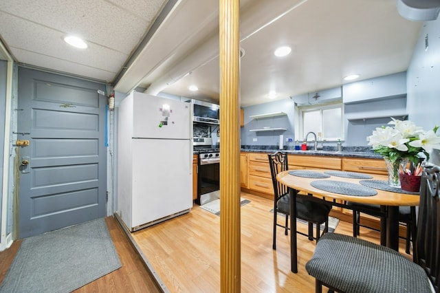 kitchen with stainless steel gas stove, white refrigerator, sink, and light hardwood / wood-style flooring