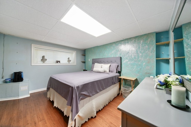 bedroom with hardwood / wood-style floors and a drop ceiling