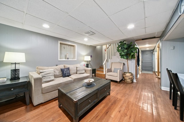 living room with a drop ceiling and light hardwood / wood-style flooring