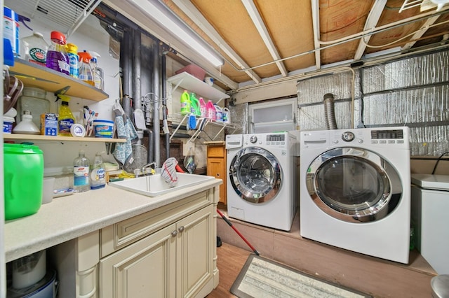 laundry area with cabinets, light wood-type flooring, washer and clothes dryer, and sink