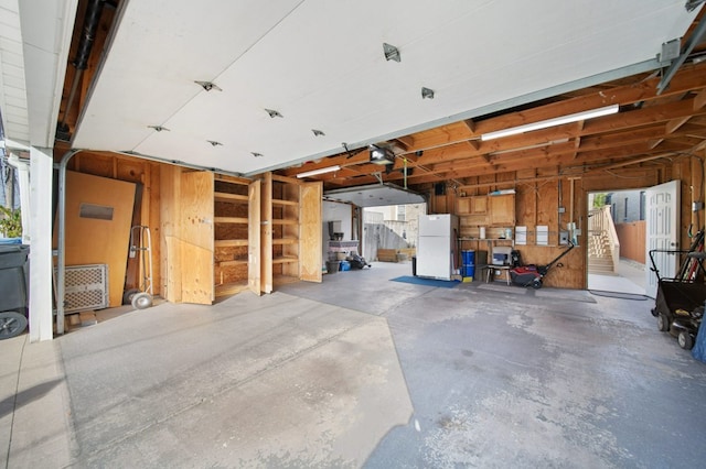 garage with wood walls, a garage door opener, and white refrigerator