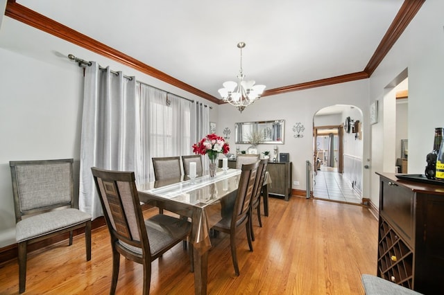 dining space featuring an inviting chandelier, ornamental molding, and light wood-type flooring