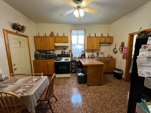 kitchen with backsplash, ceiling fan, sink, white range with gas stovetop, and a kitchen island