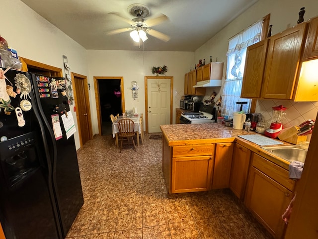 kitchen with tasteful backsplash, black refrigerator with ice dispenser, ceiling fan, and gas range gas stove