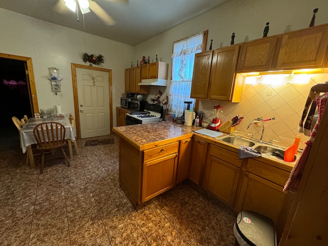 kitchen with ceiling fan, sink, kitchen peninsula, white range with gas cooktop, and decorative backsplash