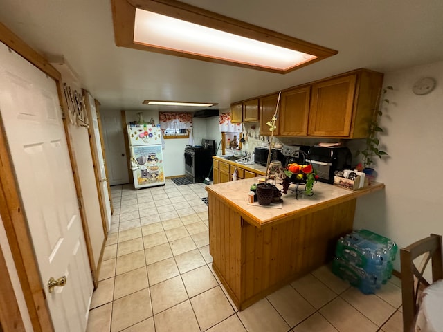 kitchen with tasteful backsplash, white refrigerator, tile countertops, kitchen peninsula, and light tile patterned floors