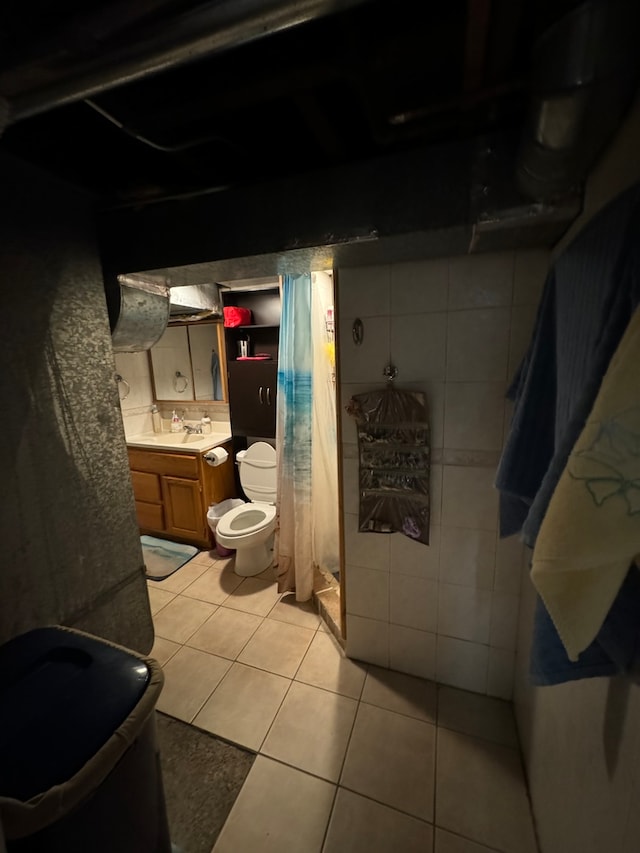 bathroom featuring tile patterned floors, vanity, toilet, and tile walls