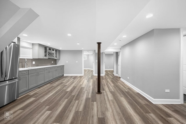 interior space with stainless steel fridge, dark hardwood / wood-style flooring, gray cabinetry, and sink