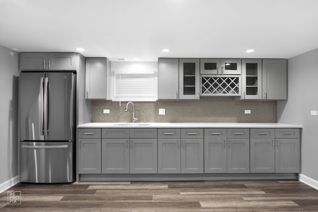 kitchen featuring stainless steel refrigerator, gray cabinetry, sink, dark wood-type flooring, and decorative backsplash