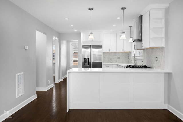 kitchen with stainless steel appliances, wall chimney range hood, kitchen peninsula, pendant lighting, and white cabinets